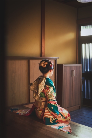梅座敷の玄関に腰かける振袖の女性の後ろ姿